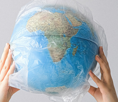 Zwei Hände halten einen in Folie verpackten Globus in die Höhe